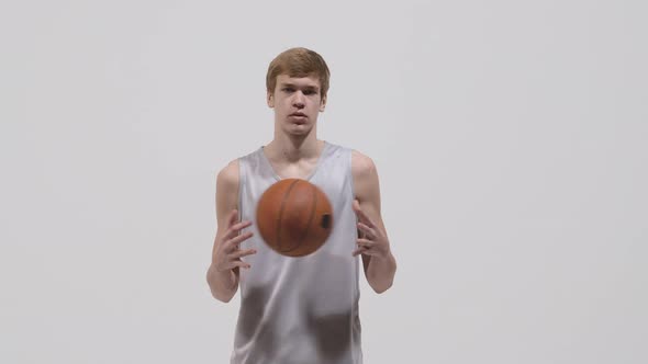 Portrait of Young Basketball Player Looking at Camera and Throwing Ball From Hand to Hand