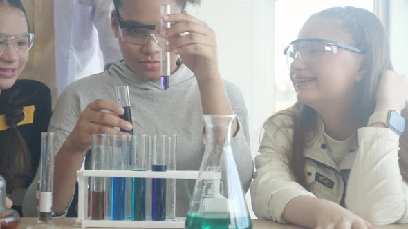 Young teacher teaching group student about science and explaining chemical for liquid in the lab.