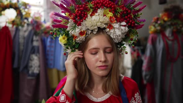 Portrait of Young Woman in Embroidered Shirt and Head Wreath Looking at Camera Stroking Hair in Slow