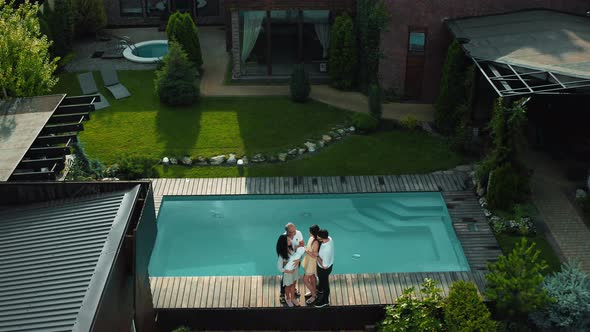 The whole family in the courtyard with a pool of his country house in a modern style