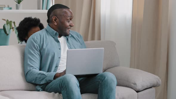 African American Father Freelancer Sitting on Sofa with Laptop Working Remotely at Home Little Cute