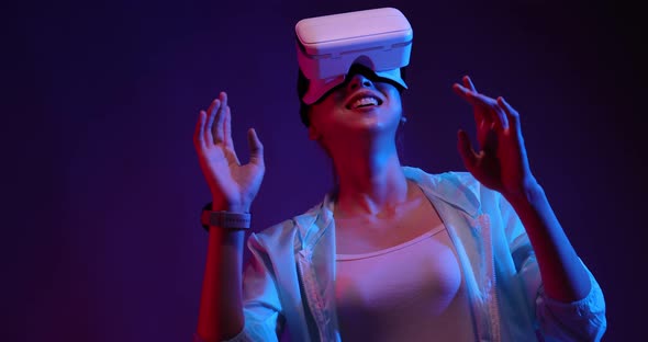 Young Asian woman playing metaverse virtual reality digital technology game with VR goggle.