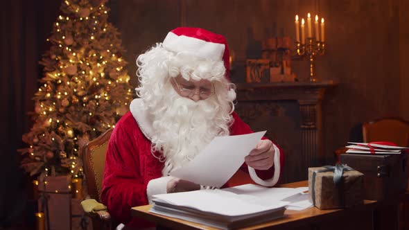 Workplace of Santa Claus. Cheerful Santa is working while sitting at the table.