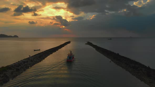 Following fisherman boat goes to the sea against sunset