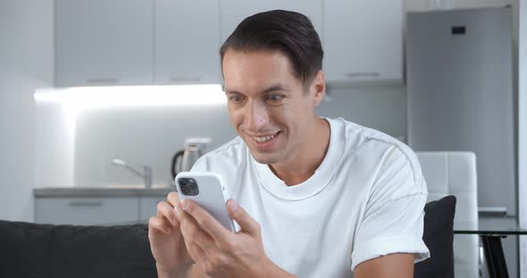 Happy Businessman Enjoying Success on Mobile Phone Sitting on Sofa at Home