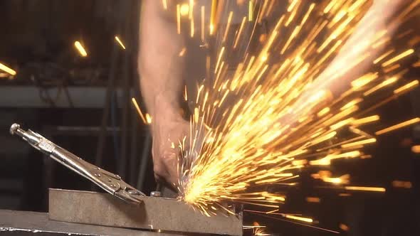 Blacksmith Working with Metal. Sparks Flying at the Camera. A Man Working Angular Grinding Machine