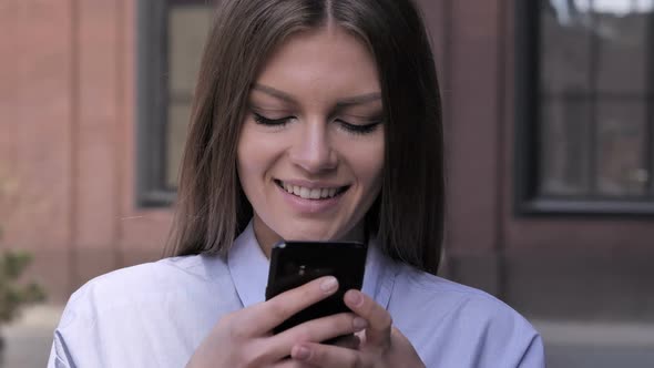 Young Woman Busy Using Smartphone Standing Outside Office