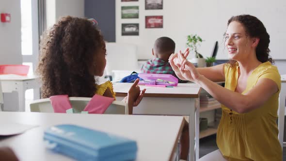 Video of happy caucasian female teacher learning math to african american girl