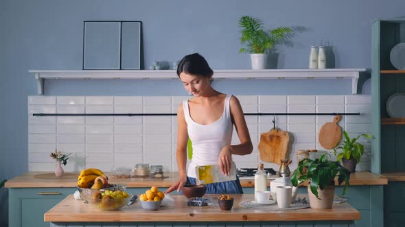 Young Woman Pouring Muesli Into A Bowl