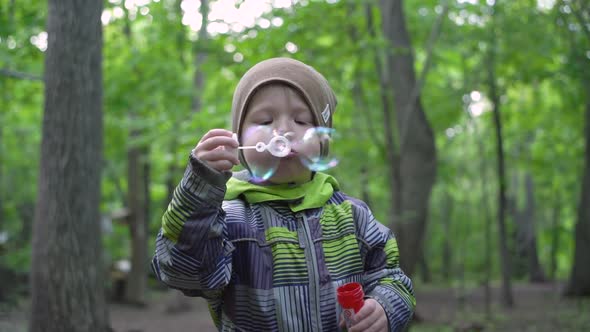 Portrait of a boy blowing soap bubbles in the forest