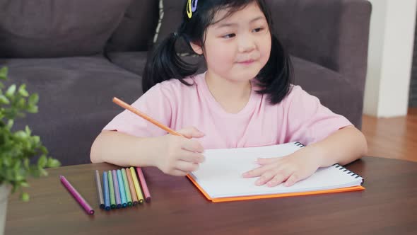 Asia japanese woman child kid relax rest fun happy draw cartoon in sketchbook lying on sofa.