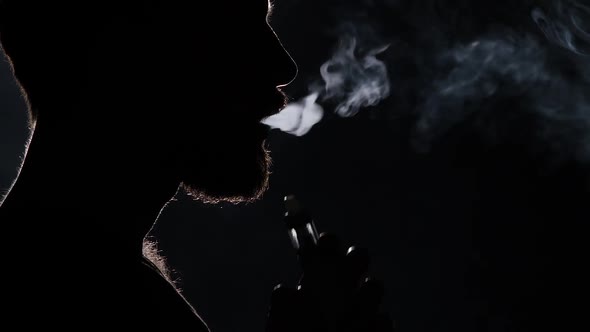 Man Smoking Electronic Cigarette on Black. Silhouette. Close Up