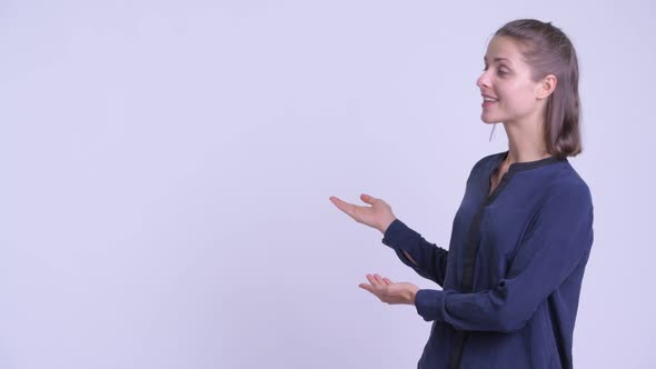 Happy Young Beautiful Businesswoman Talking and Showing Something To the Back