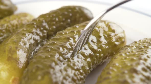 Closeup of piercing a pickle with a metal shiny fork