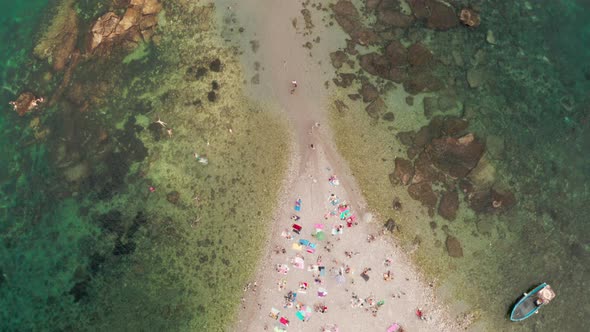 Top down aerial view of a sand bridge connecting two beaches, surrounded by a shallow sea with a cle