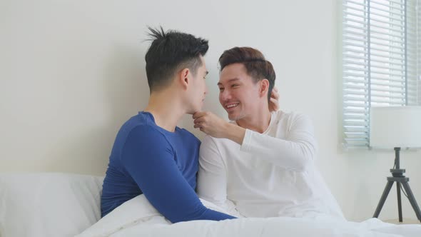 Asian handsome male gay couple sitting on bed and look at each other.