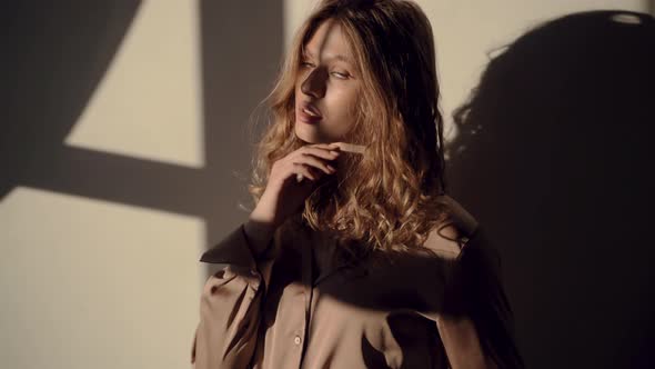 Beautiful European Girl in a Silk Shirt in the Sun Looks at the Camera