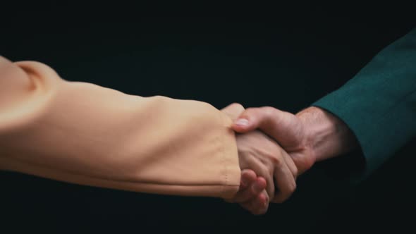 Two Businessmen Shake Hands on a Black Background Good Deal