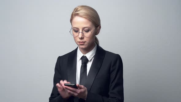 businesswoman in a classic business suit typing on mobile phone