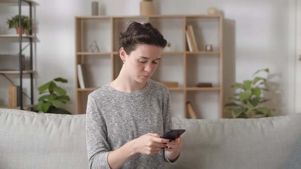 Worried Nervous Young Woman Writes Message on Smartphone at Home