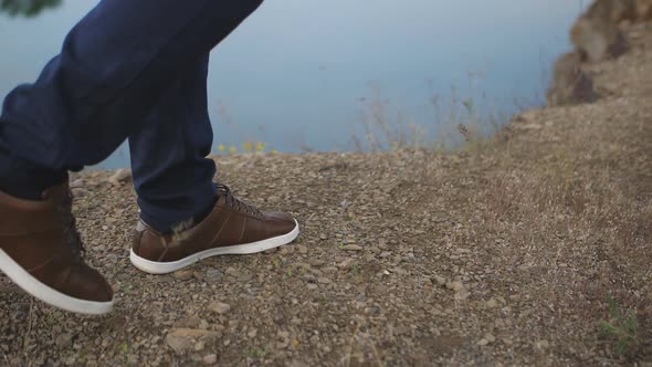 Closeup of the Legs of a Man Walking Along the Shore of a Pond