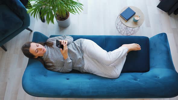 Overhead Shot of Happy Relaxed Woman Holding Smart Phone Using Mobile Apps Watching Funny Video