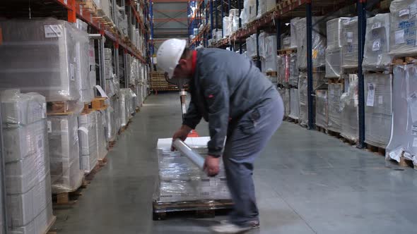 A Man in a Helmet and Uniform Packs a Pallet