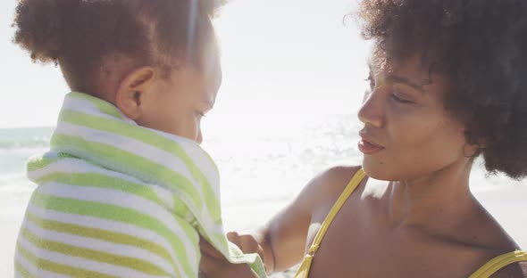 Smiling african american mother toweling off her daughter on sunny beach