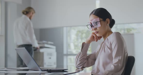 Tired Businesswoman Sleeping at Workplace with Stickers on Eyes