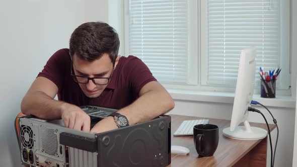 Young Professional Worker Repair a Broken Computer in the Office Using a Screwdriver and Upgrading