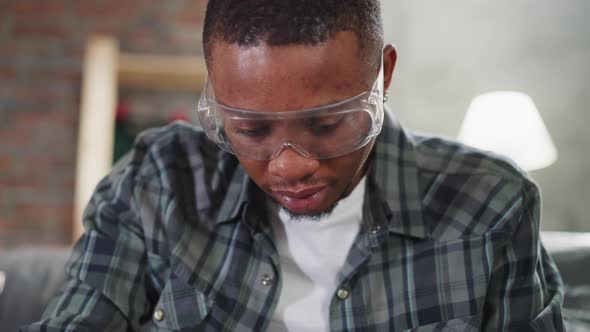 AfricanAmerican Man with Goggles Works Sitting on Sofa