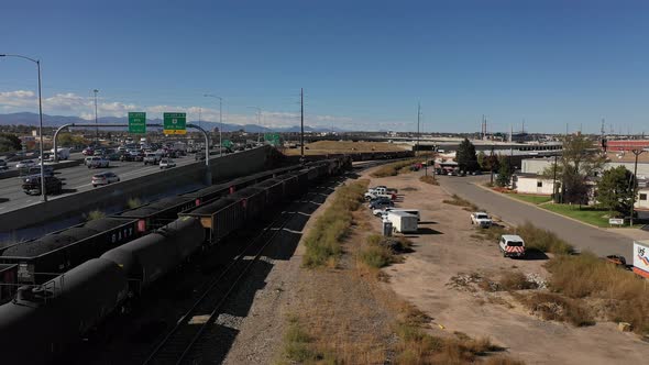 Freight trains rumble along and a clear day along a busy freeway