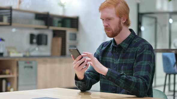 Beard Redhead Man Using Smartphone in Cafe 