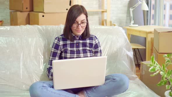 Portrait Young Joyful Woman Uses Laptop Sitting on the Couch After Moving To a Modern Apartment