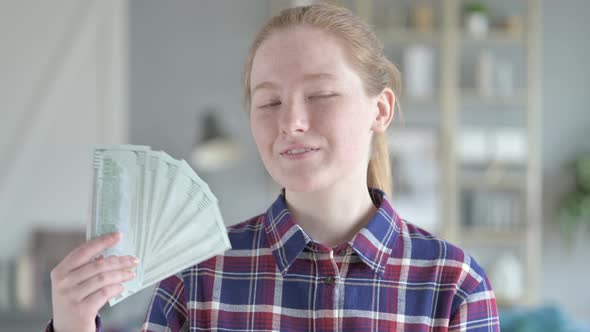 Young Woman Fanning Herself With Dollars