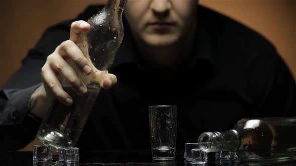 Depressed Blurred Man Drinking Vodka Alone in a Dark Room. Concept of Alcoholism