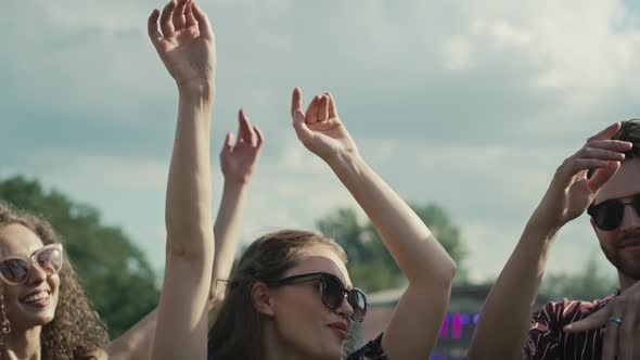 Young caucasian friends dancing on music festival with hands up. Shot with RED helium camera in 8K.