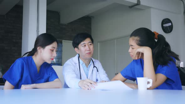 Group of Young Asian Doctor and Nurse Sitting During Break Discussing Serious Patient Case