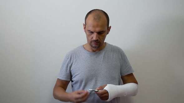 Man with Arm in Plaster Cast Taking Pill in Studio