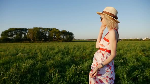 Girl in a straw hat walks in a summer meadow.