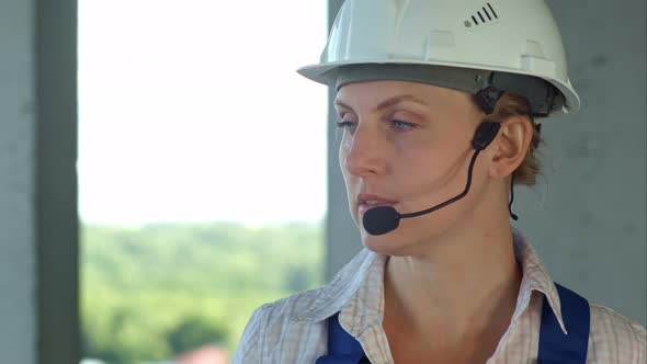 Builder Supervisor Oversees Building Site and Gives Instructions To Workers Over the Intercom alt