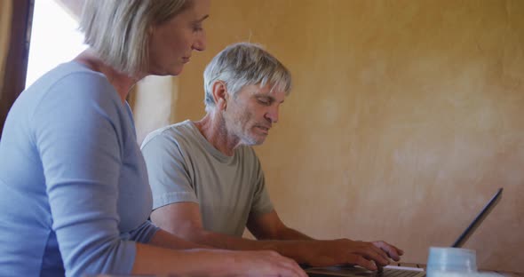 Senior caucasian couple using laptop and sitting at table