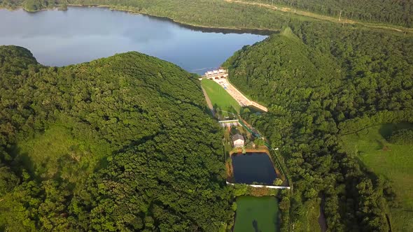 Drone View of Smooth Water and a Dam Surrounded By Green Hills