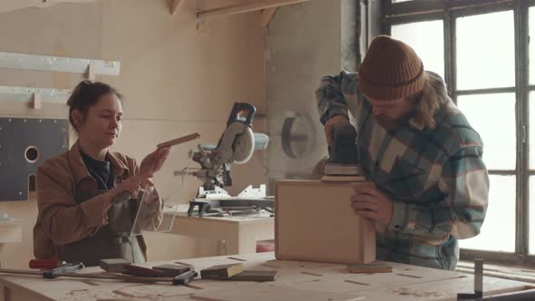 Two People Sanding Wooden Box in Joinery Workshop