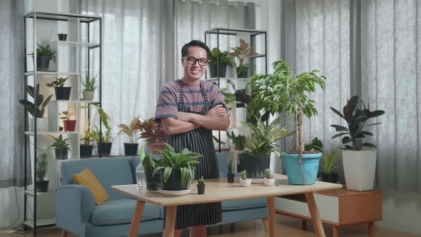 Asian Man With Plants Crossing His Arms And Smiling To Camera At Home