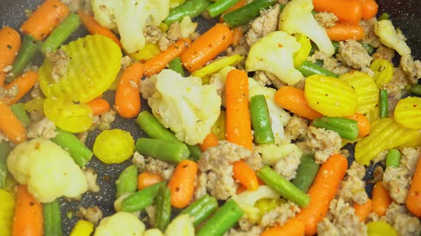 Close up view of steaming frying pan and mixed vegetables with frying minced.