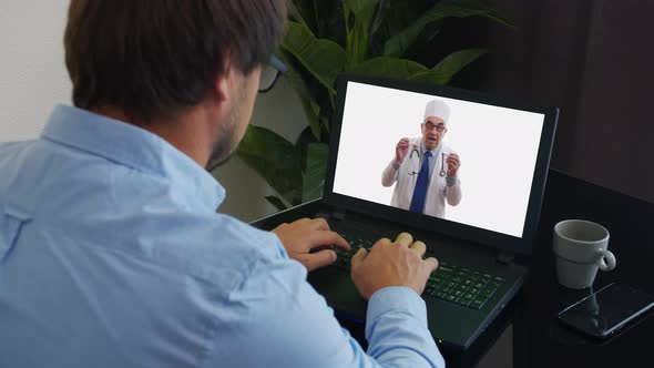 Senior Male Doctor Wears White Medical Coat, Stethoscope, Headset Makes Distant Video Call. Old