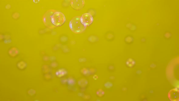 Beautiful Colored Soap Bubbles Fly Indoors on a Yellow Background