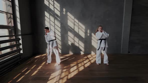 Dark-Haired Korean Boy and A European Blonde Girl Warm up In Training Class