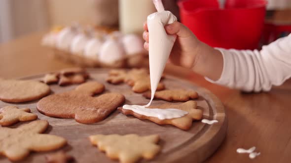 Little Girl in Santa Hat Decorates Gingerbread at Home